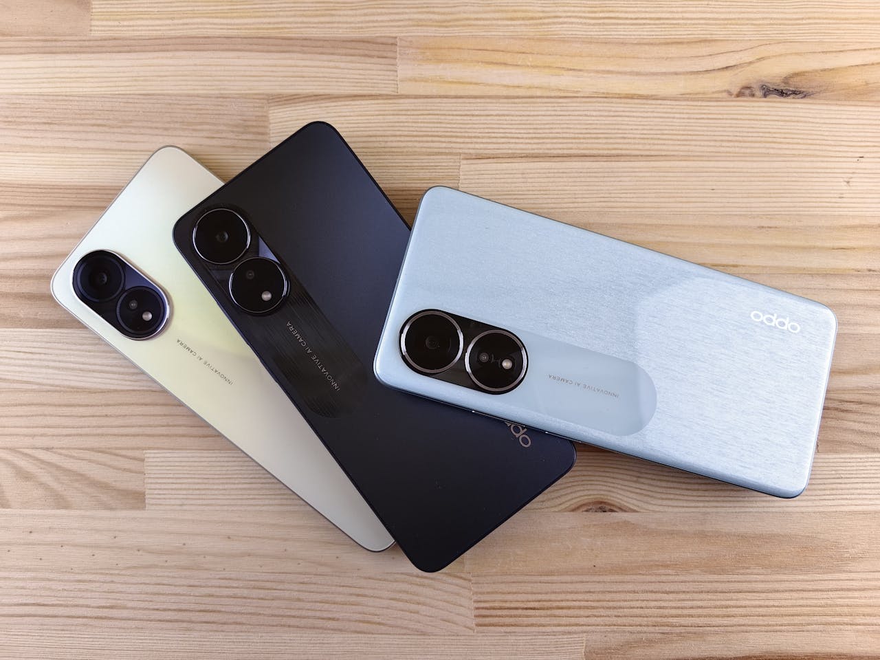 hero-img-01 Three modern smartphones displayed on a wooden surface, showcasing design and color variants.